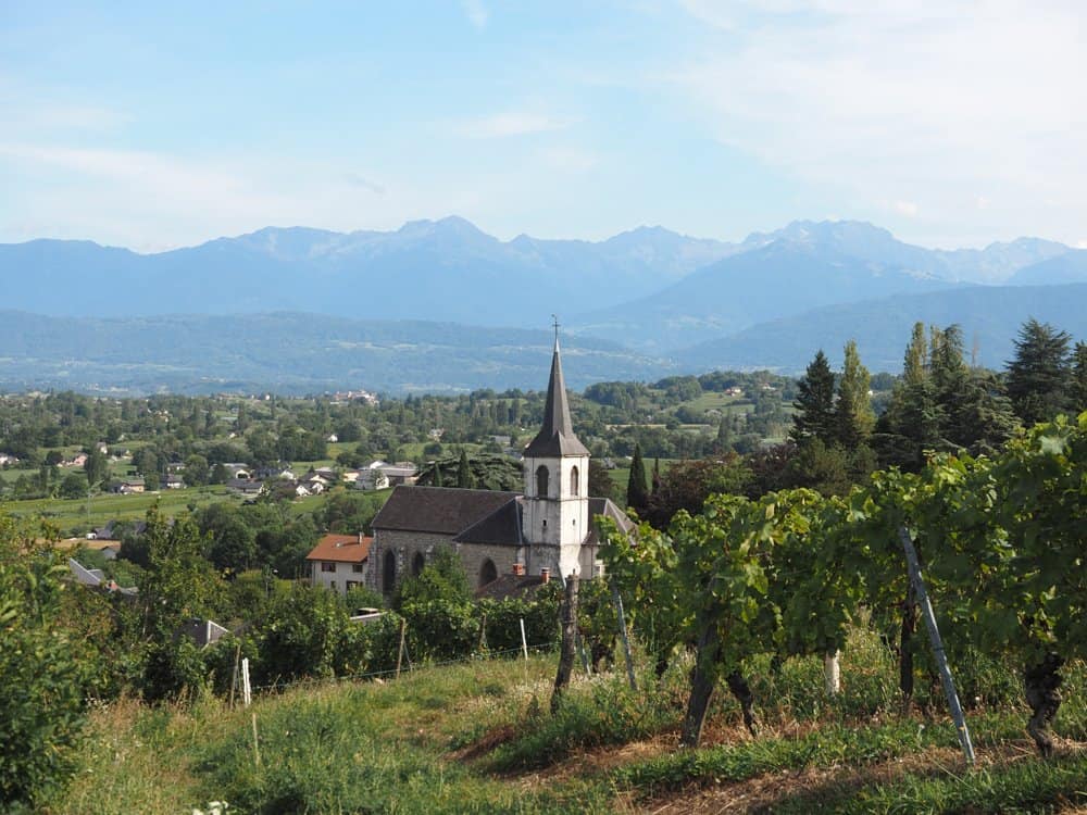 Church in the middle of the photo with mountains in the background in the Savoie