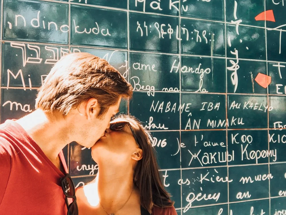 Kat and Chris kissing at the Love Wall in Paris