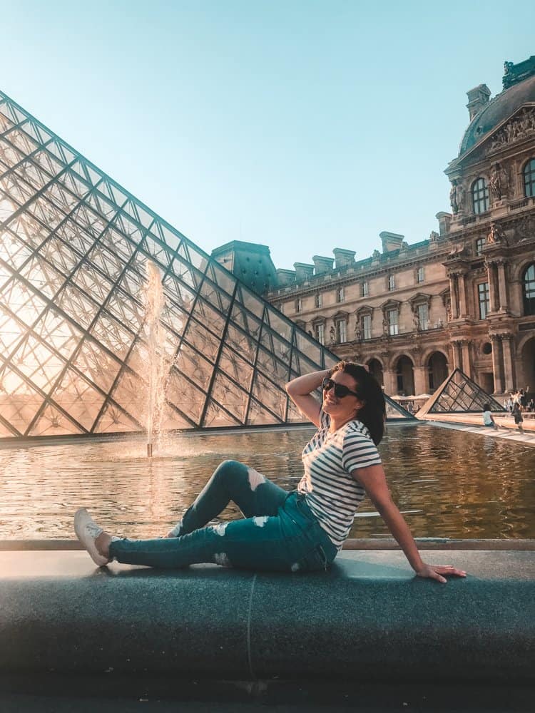 Kat sitting with her hand in her hair in front of the Louvre