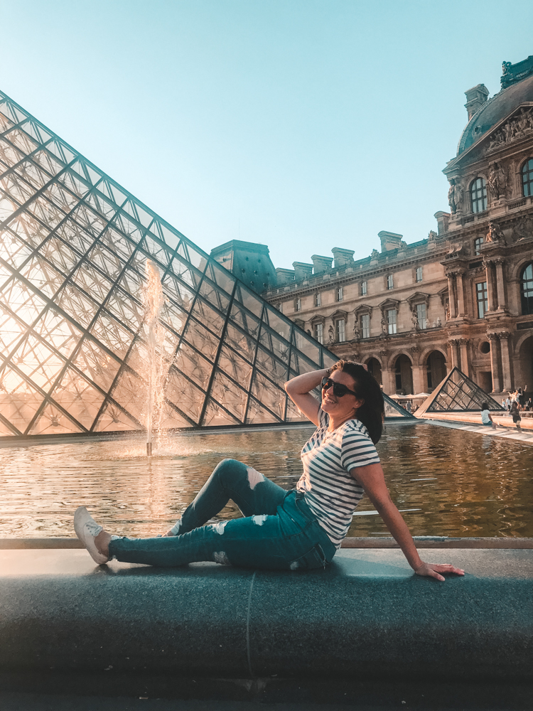 Kat sitting by the fountain at the Louvre with her hand in her hair