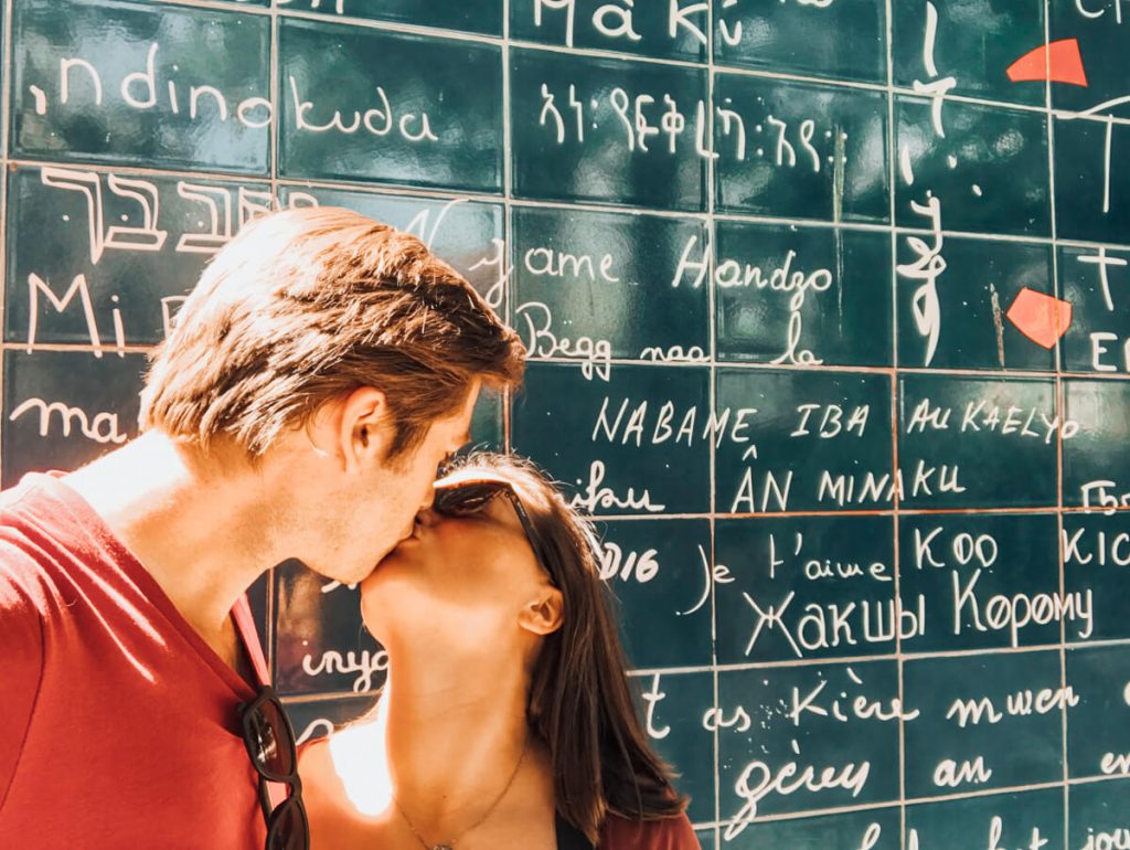 Kat and Chris kissing in front of the Love Wall in Paris