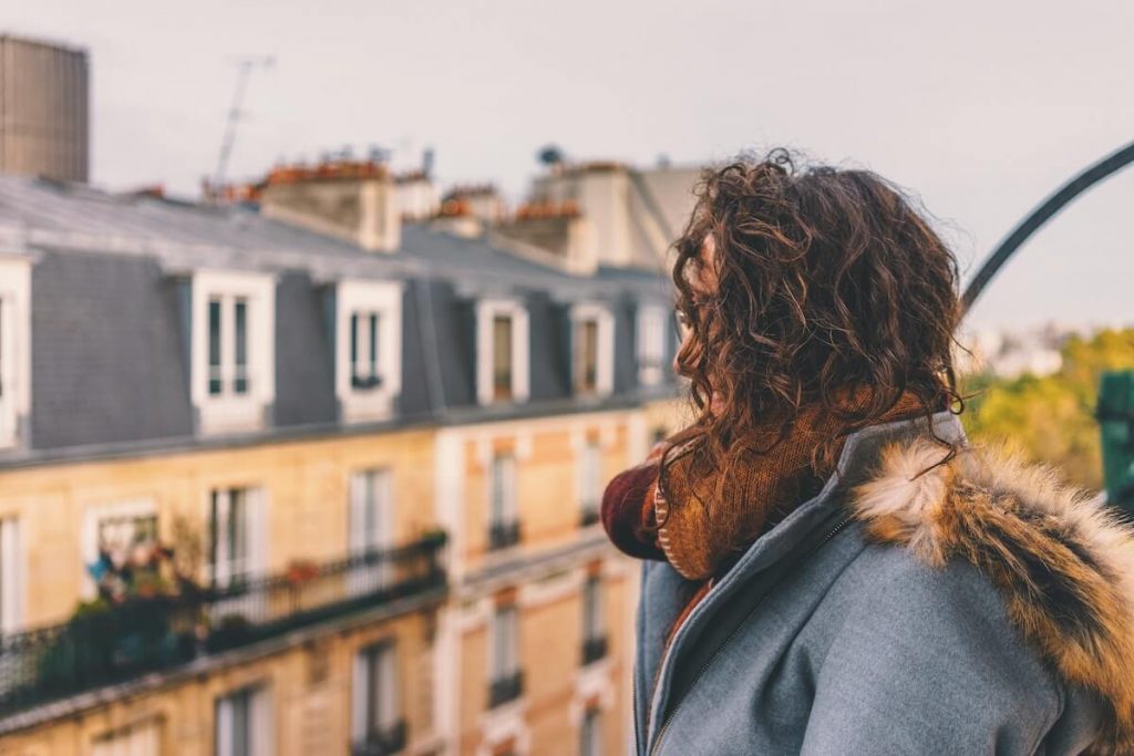 Girl looking from her balcony in the fall - Best Time to Visit Paris