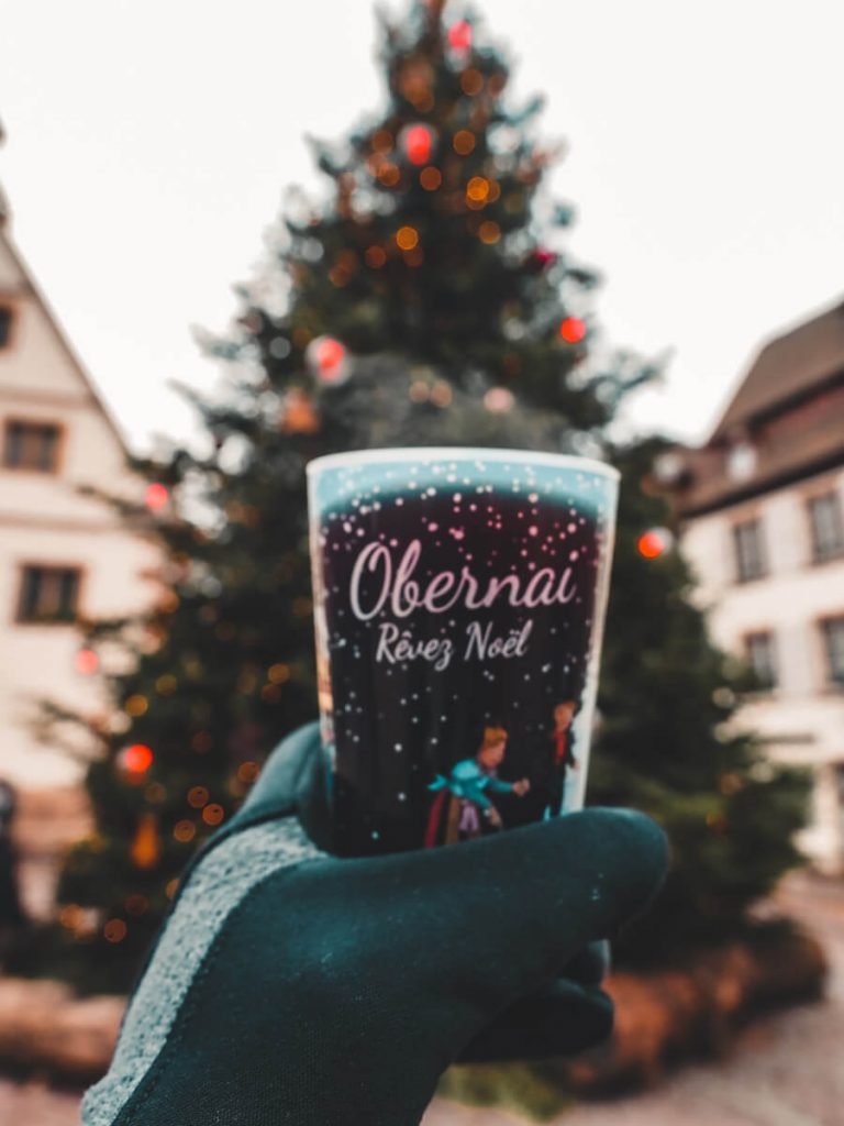 Obernai mulled wine in a cup being held in front of the Christmas tree.jpg