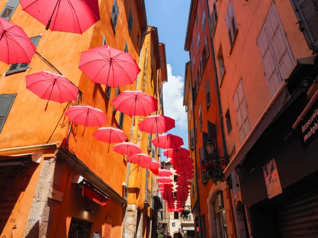 Colorful street with pink umbrellas overhead