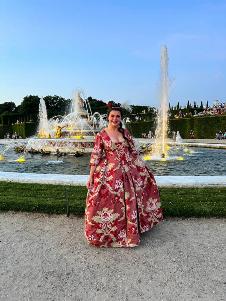 Kat in front of a fountain in the gardens of Versailles 2