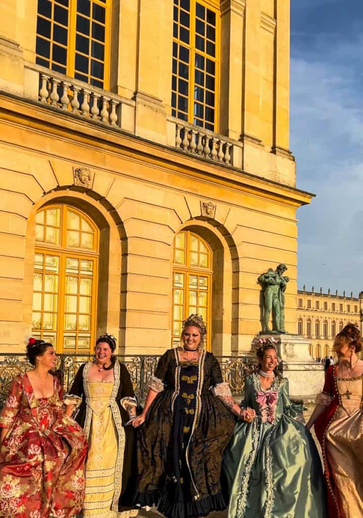 Kat and friends skipping at Versailles in their 18th century ball gowns