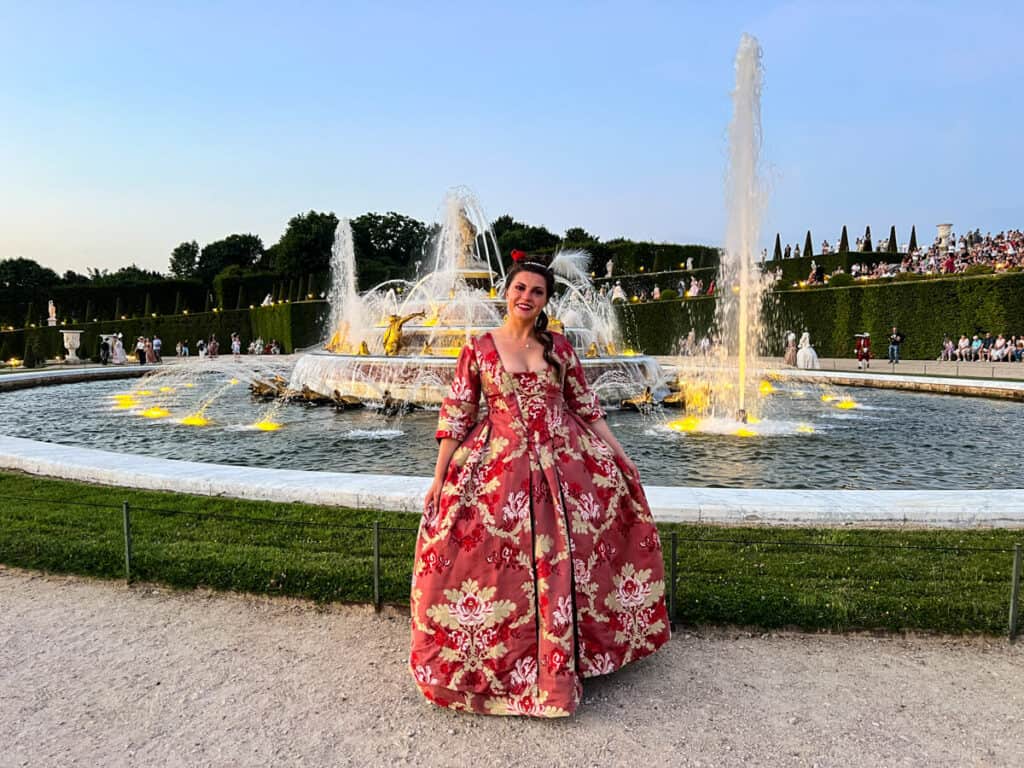 Kat in front of a fountain in the gardens of Versailles 2