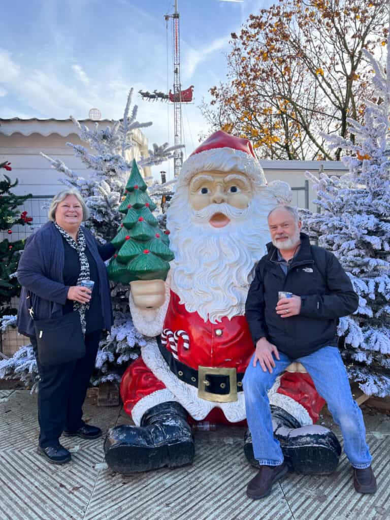 Kat's parents posing with a Santa decoration at the Tuileries Christmas Market in Paris