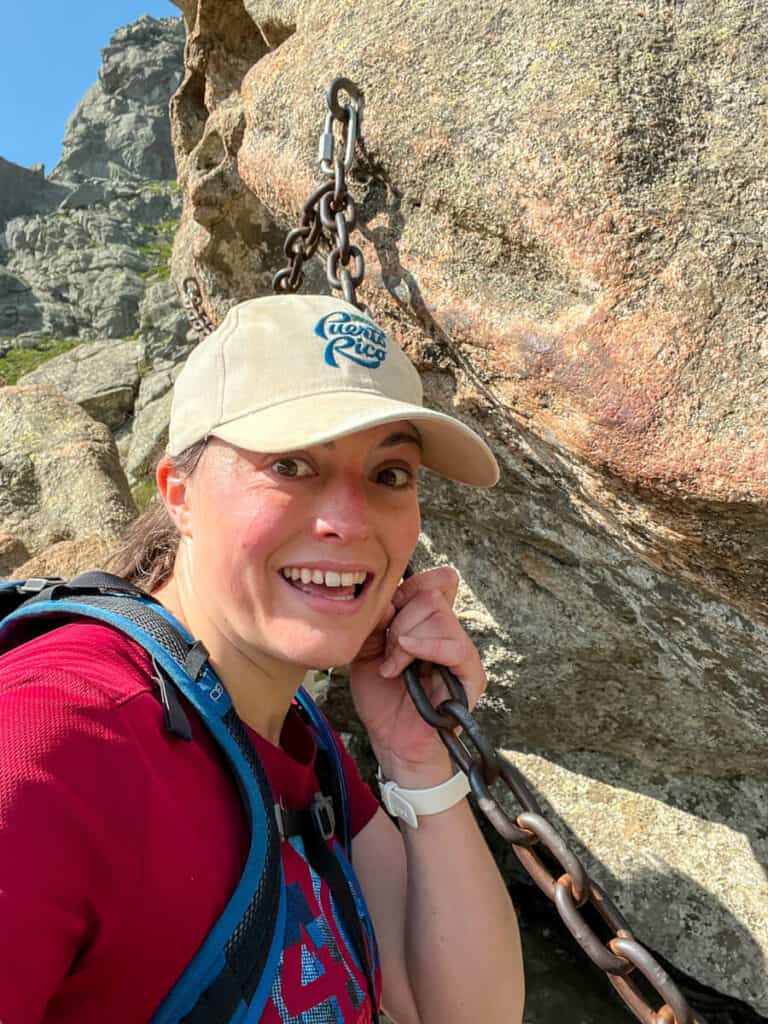 Kat freaking out about having to climb down a boulder using a chain and holding said chain on the Aiguilles de Bavella Loop