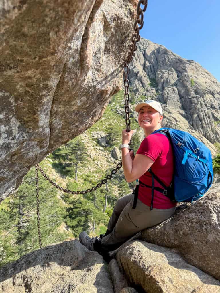 Kat smiling and hanging on to the chain while hiking in Corisca