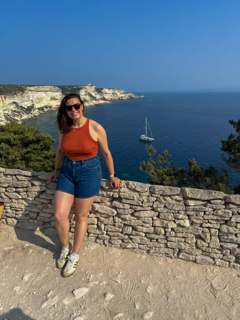 Kat smiling with the Cliffs of Bonifacio behind her