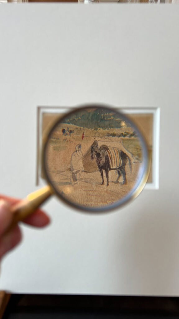 Art being magnified with a magnifying glass while at the Consultation Room at the Louvre
