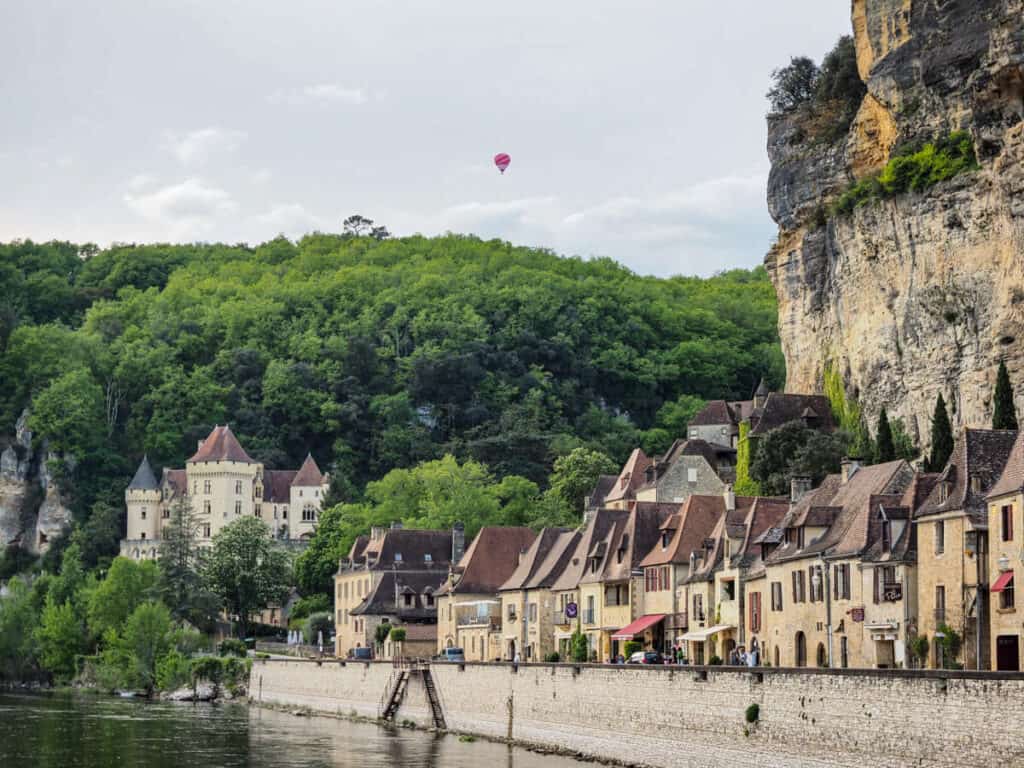 La Roque-Gageac with hot air balloon rising into air in the background